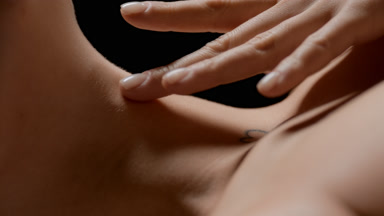 Extreme close-up shot of woman with heart tattoo strokes neck