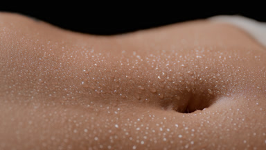 Macro shot of woman's wet flat belly moving while breathing