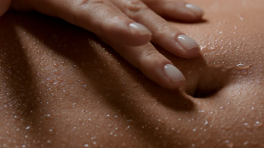 Macro shot of slim woman strokes her wet good-looking flat belly