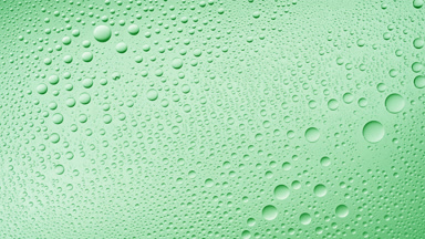 Water drops blown off the wet glass surface on green background