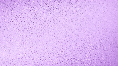 Medium size water drops blown off the glass surface on purple bg