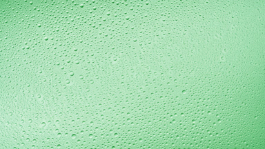 Medium size water drops blown off the glass surface on green bg