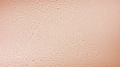 Medium size water drops blown off the glass surface on beige bg