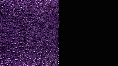 Purple water drops blown off the wet glass surface on black bg