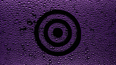 Purple target sign blown off the wet glass on black background