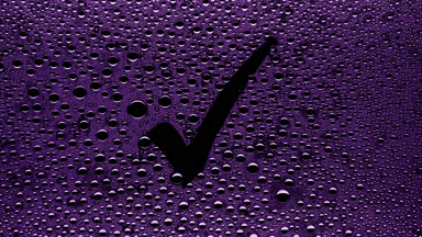 Purple checkmark sign blown off the wet glass on black bg
