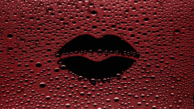 Red lip shape print blown off the wet glass on black background