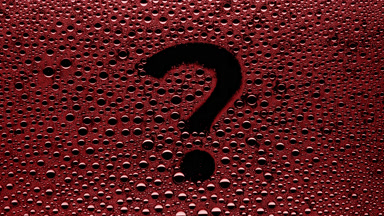 Red question mark blown off the wet glass on black background