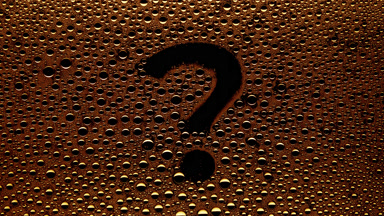 Orange question mark blown off the wet glass on black background