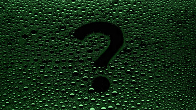 Green question mark blown off the wet glass on black background