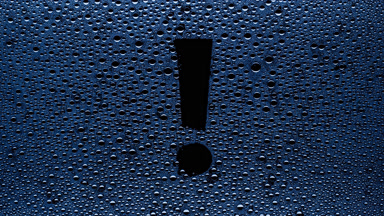 Blue exclamation sign blown off the wet glass on black bg