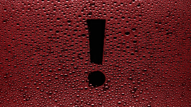 Red exclamation sign blown off the wet glass on black background