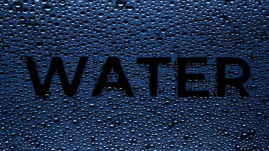 Blue water inscription blown off the wet glass on black bg