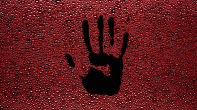 Red handprint blown off the wet glass on black background