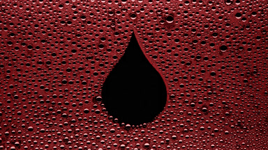 Red drop shape print blown off the wet glass on black background