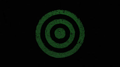 Green target sign blown off the wet glass on black background