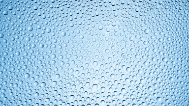 Drops from the wet glass being blown off on blue background