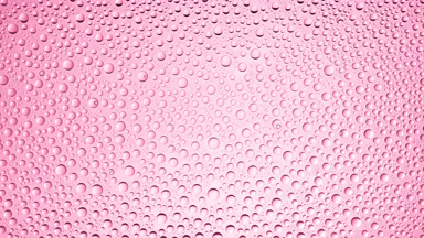 Drops from the wet glass being blown off on pink background
