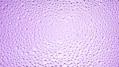 Drops from the wet glass being blown off on purple background