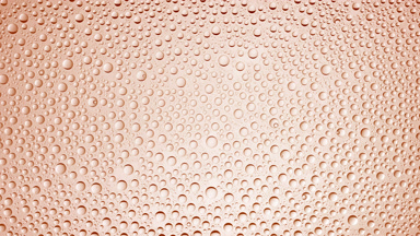 Drops are being blown off the half of the wet glass on purple background