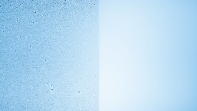 Drops are being blown off the half of the wet glass on a purple bg