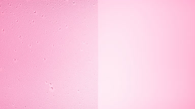 Drops are being blown off the half of the wet glass on a pink bg
