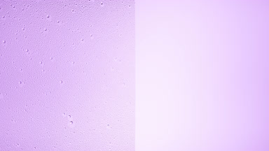 Drops are being blown off the half of the wet glass on a purple bg