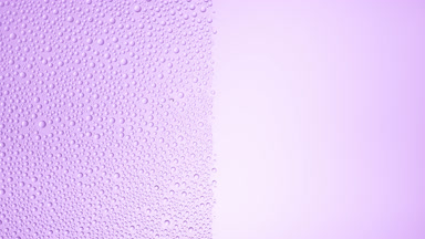 Drops are being blown off the half of the wet glass on a purple bg