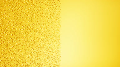 Drops are being blown off the half of the wet glass on a yellow bg