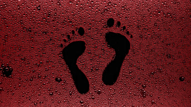 Red footprints blown off the wet glass on black background