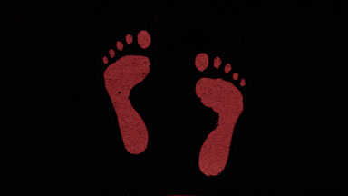 Red inverted footprints blown off the wet glass on black bg
