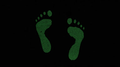 Green inverted footprints blown off the wet glass on black bg
