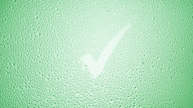 Checkmark blown off the wet glass on green background