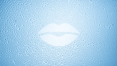 Lip shape print blown off the wet glass on blue background