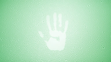 Handprint blown off the wet glass on green background