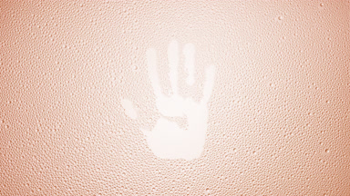 Handprint blown off the wet glass on beige background