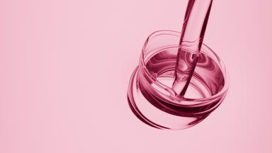 Pink oil is being poured into pink oil on pale pink background