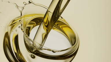 Almond oil is being poured into yellow oil on white background