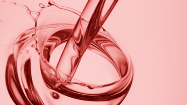 Rose oil is being poured into rose oil on pale pink background