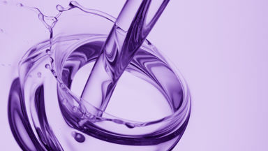 Lavender oil is being poured into oil on purple background
