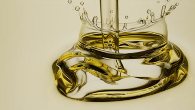 Macro of pale yellow oil is being poured into pale yellow oil