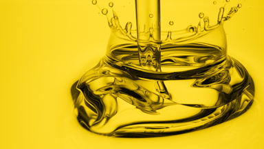 Side view macro of yellow oil is being poured into yellow oil