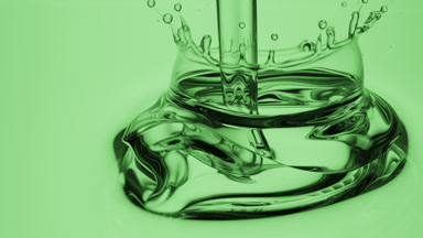Side view macro shot of green oil is being poured into green oil