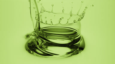 Side view macro of avocado oil is being poured into green oil
