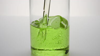 Grapeseed oil being poured into empty beaker on grey background