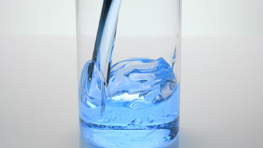 Cyan oil is being poured into empty beaker on grey background