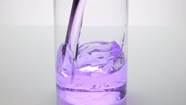 Bakuchoil is being poured into empty beaker on grey background