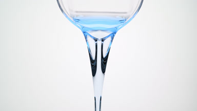 Cyan oil is being poured from beaker on grey background