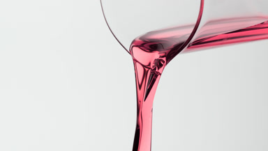 Macro of pink oil is being poured from beaker on grey background