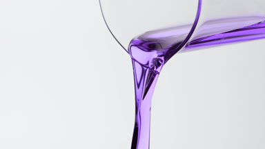 Purple oil is being poured from beaker on grey background